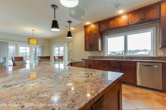 kitchen with pendant lighting, sink, dishwasher, light stone counters, and a textured ceiling