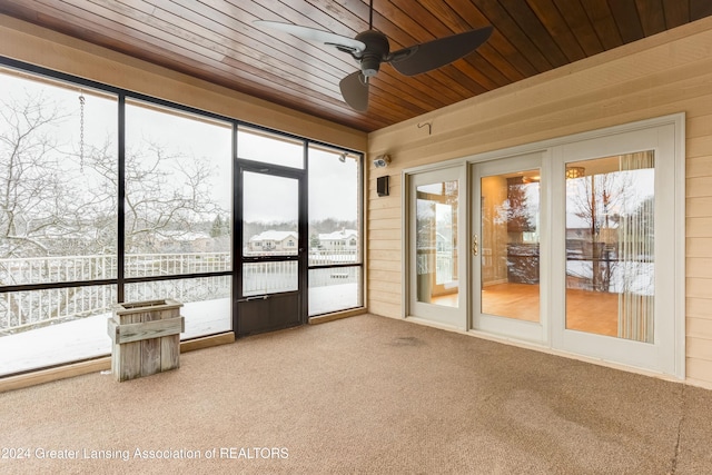 unfurnished sunroom featuring a healthy amount of sunlight, wooden ceiling, and ceiling fan