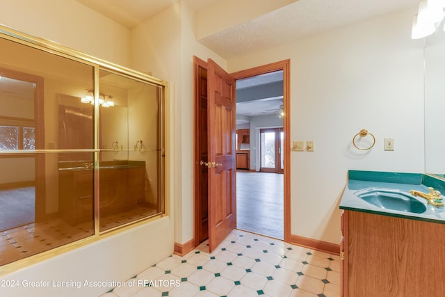 bathroom with vanity, a textured ceiling, and shower / bath combination with glass door