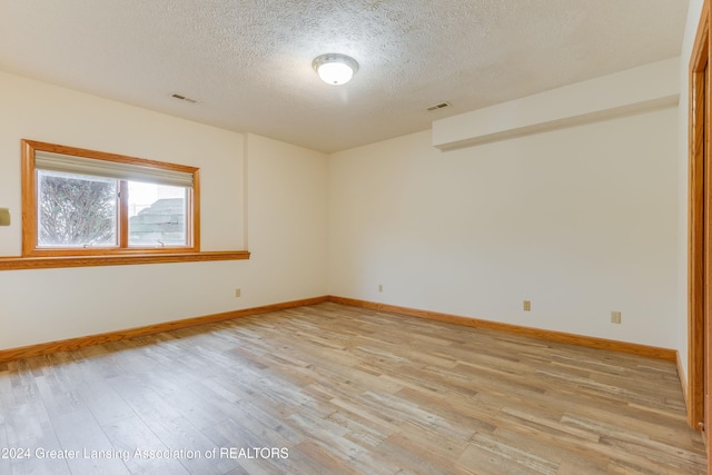 empty room featuring a textured ceiling and light hardwood / wood-style floors