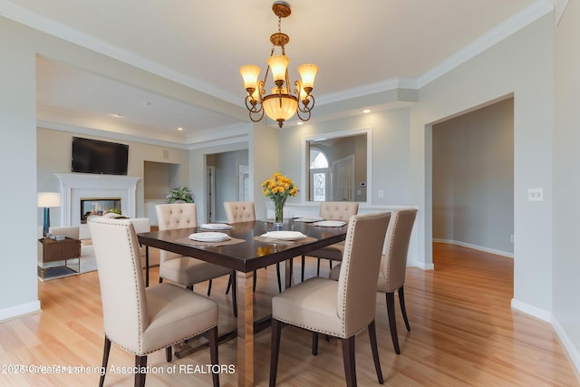 dining space featuring crown molding, a chandelier, and light hardwood / wood-style flooring