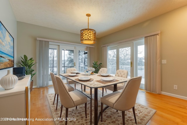 dining area with a textured ceiling and light hardwood / wood-style floors