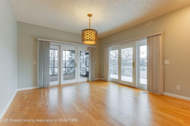 empty room with light hardwood / wood-style floors and a textured ceiling