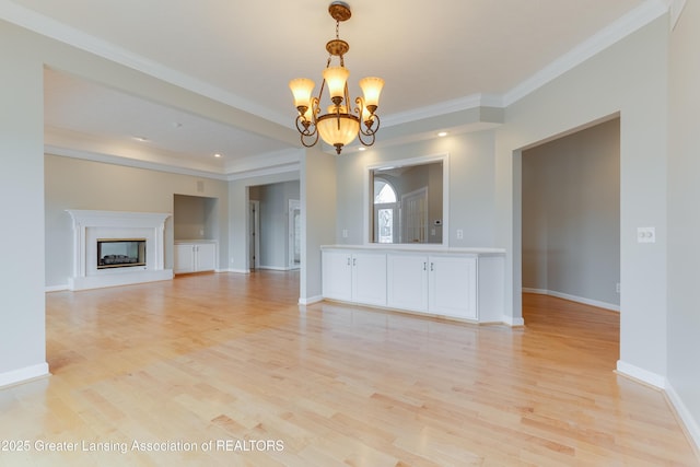 unfurnished living room featuring ornamental molding, a notable chandelier, and light wood-type flooring