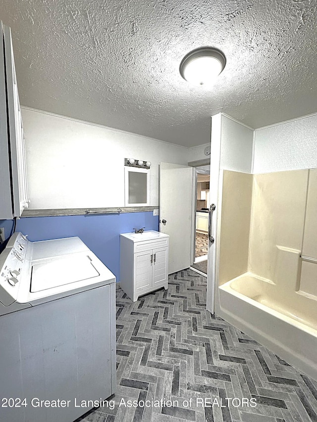 clothes washing area with washing machine and clothes dryer and a textured ceiling