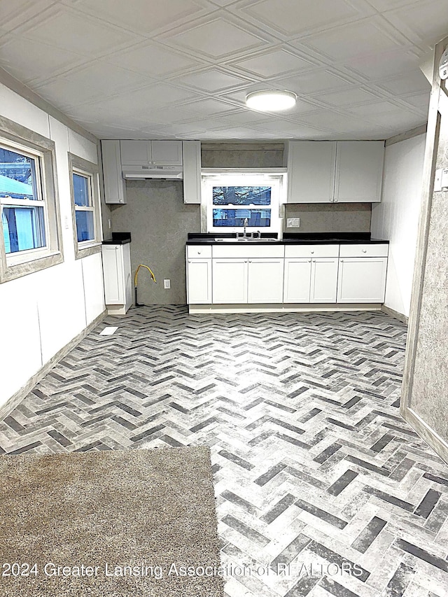 kitchen with white cabinetry, sink, and light carpet