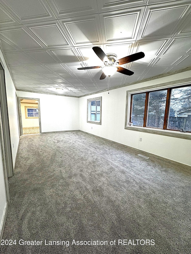 carpeted empty room featuring a wealth of natural light and ceiling fan