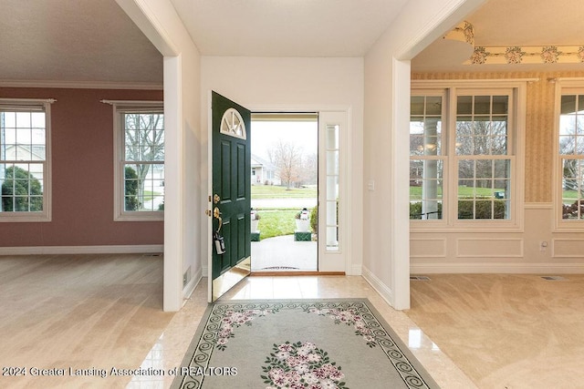 tiled foyer featuring ornamental molding and a healthy amount of sunlight