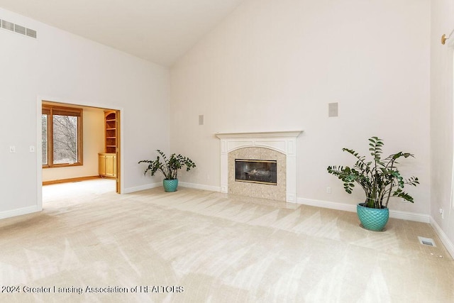 living room with a high end fireplace, high vaulted ceiling, and light colored carpet