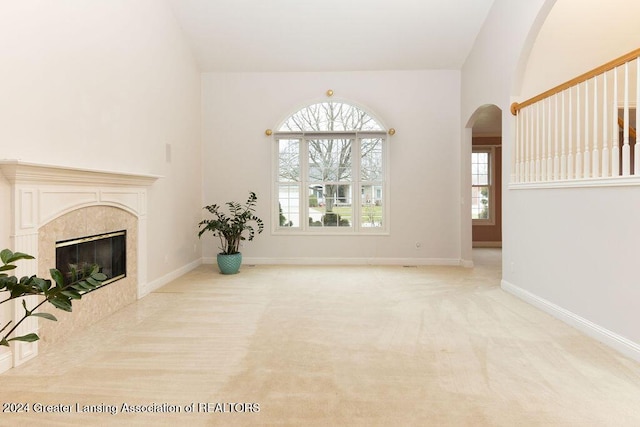 unfurnished living room featuring light colored carpet, vaulted ceiling, and a premium fireplace