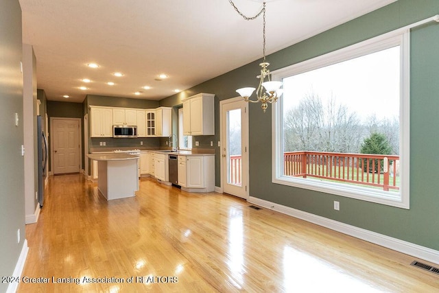 kitchen with a center island, white cabinets, sink, hanging light fixtures, and stainless steel appliances