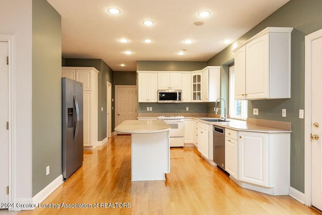 kitchen featuring white cabinetry, sink, a center island, appliances with stainless steel finishes, and light wood-type flooring