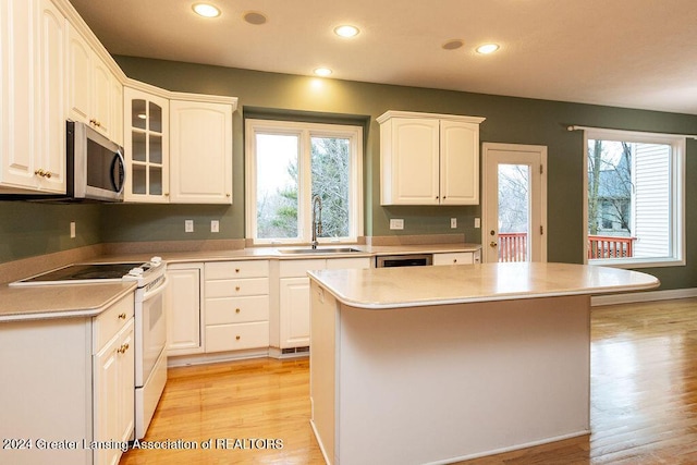 kitchen with electric range, white cabinetry, a wealth of natural light, and sink