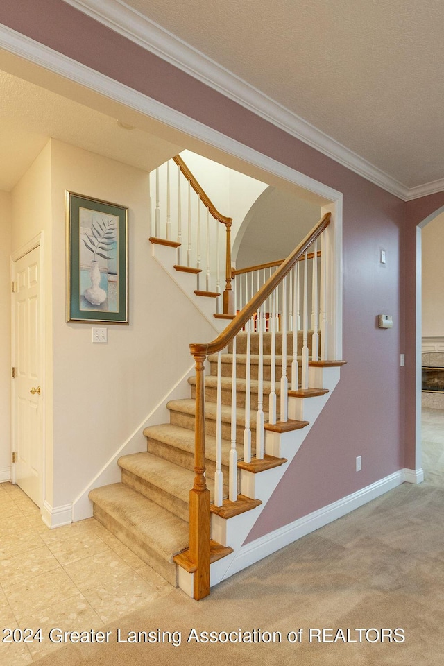 staircase with carpet floors and crown molding