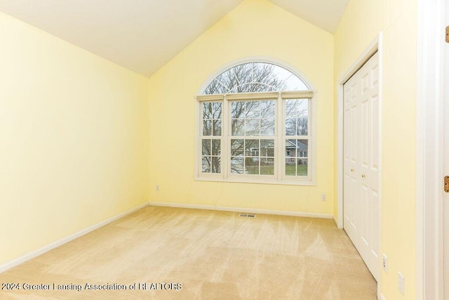 empty room featuring light colored carpet and lofted ceiling