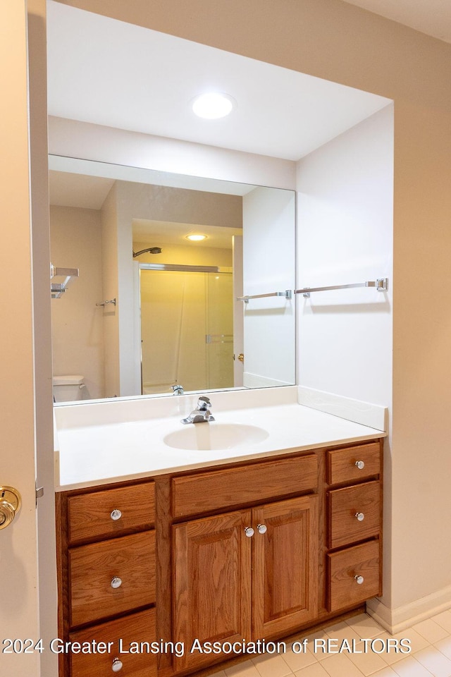 bathroom featuring tile patterned floors, toilet, vanity, and walk in shower