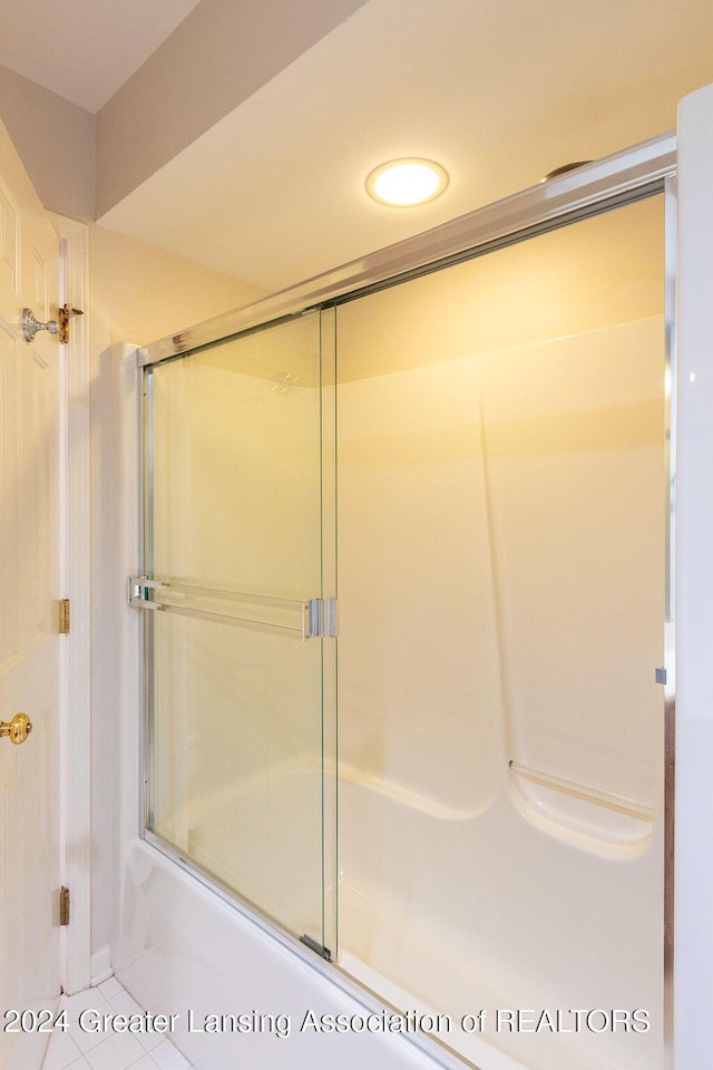 bathroom with tile patterned floors and bath / shower combo with glass door