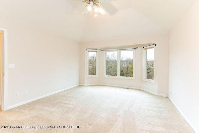 spare room with ceiling fan, lofted ceiling, and light carpet