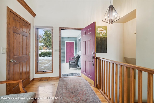 entrance foyer featuring hardwood / wood-style floors, a notable chandelier, and ornamental molding