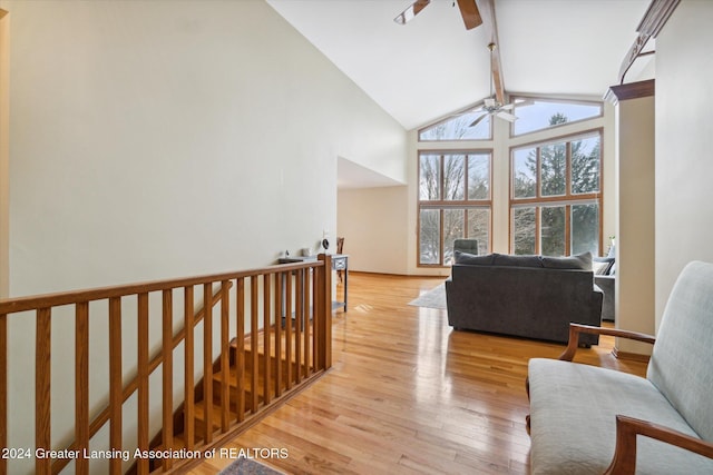 living room with beamed ceiling, light wood-type flooring, high vaulted ceiling, and ceiling fan