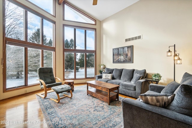 living room featuring plenty of natural light, ceiling fan, light wood-type flooring, and high vaulted ceiling