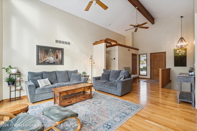 living room featuring beamed ceiling, high vaulted ceiling, ceiling fan with notable chandelier, and hardwood / wood-style flooring