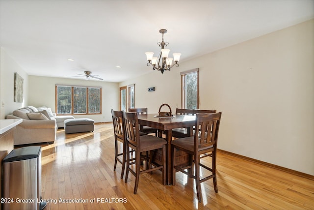 dining area with ceiling fan with notable chandelier and light wood-type flooring