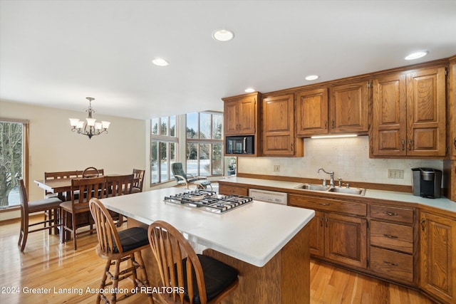 kitchen featuring stainless steel gas cooktop, sink, decorative light fixtures, a center island, and plenty of natural light