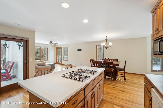 kitchen featuring decorative light fixtures, light hardwood / wood-style floors, a kitchen island, and stainless steel gas stovetop