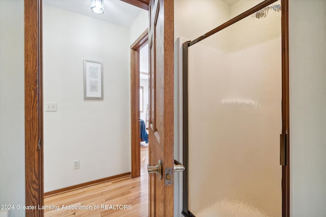 bathroom with wood-type flooring and a shower with shower door