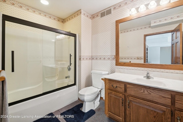 full bathroom featuring vanity, bath / shower combo with glass door, and toilet