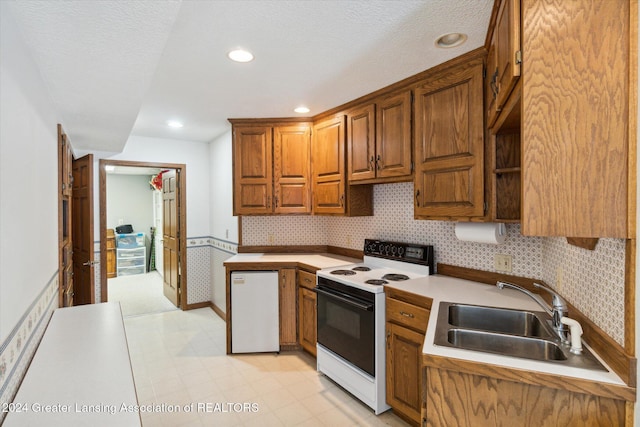 kitchen with a textured ceiling, sink, and white appliances