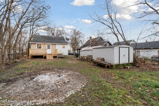 rear view of property with a deck and a storage unit