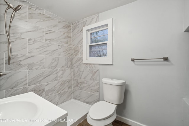 bathroom featuring a tile shower, vanity, and toilet