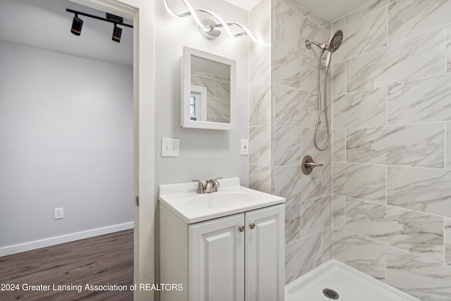 bathroom with hardwood / wood-style floors, vanity, and a tile shower