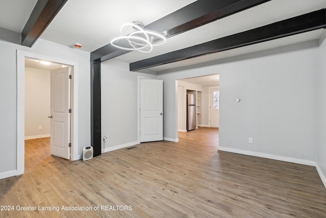 unfurnished room with beam ceiling, a notable chandelier, and light wood-type flooring