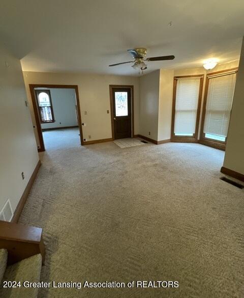 unfurnished living room with ceiling fan and light colored carpet