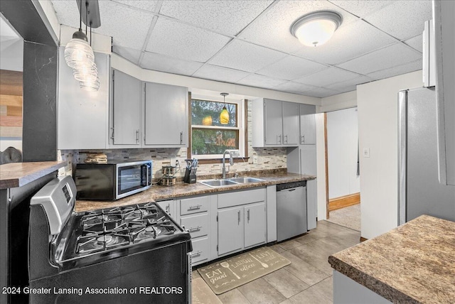 kitchen featuring a drop ceiling, hanging light fixtures, sink, decorative backsplash, and appliances with stainless steel finishes