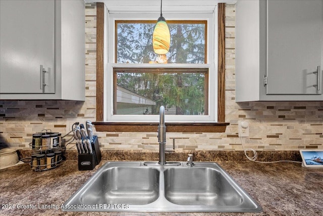 kitchen with backsplash, decorative light fixtures, gray cabinets, and sink