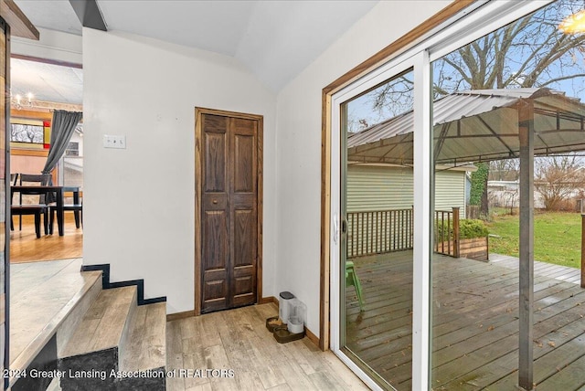 doorway featuring a healthy amount of sunlight, light hardwood / wood-style floors, and lofted ceiling