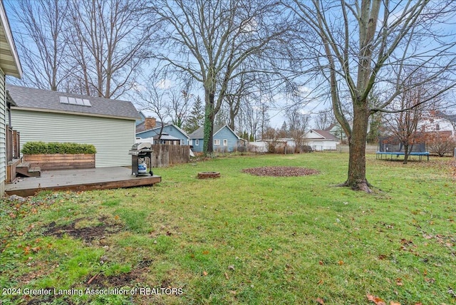 view of yard with a wooden deck, a fire pit, and a trampoline