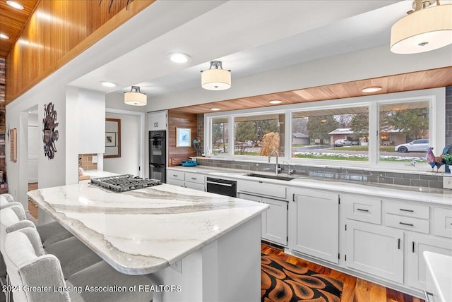 kitchen featuring a kitchen breakfast bar, backsplash, white cabinetry, and sink