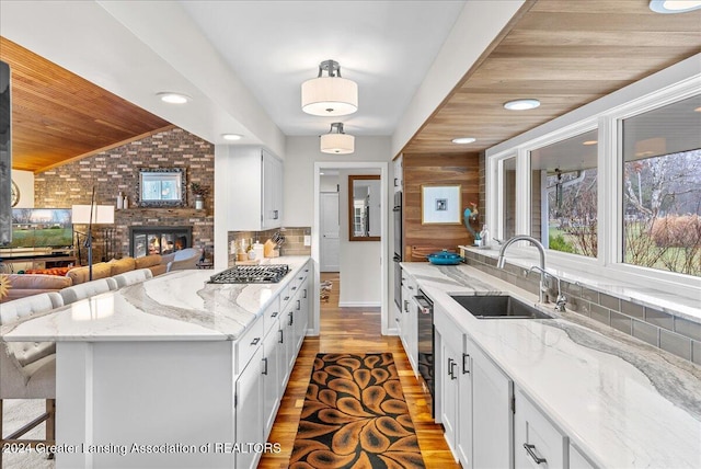 kitchen with a fireplace, white cabinetry, and sink