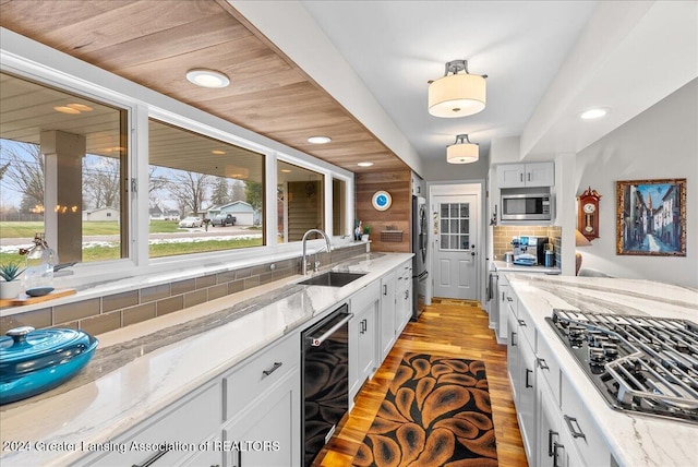 kitchen featuring light stone countertops, white cabinetry, beverage cooler, and stainless steel appliances