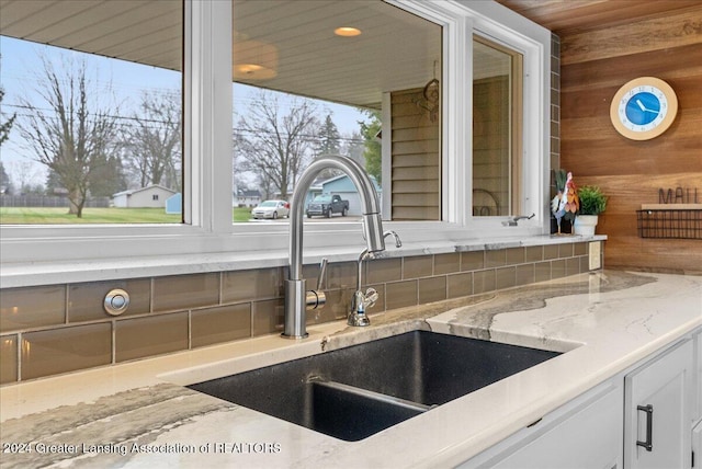 interior details featuring light stone counters, sink, and wooden walls