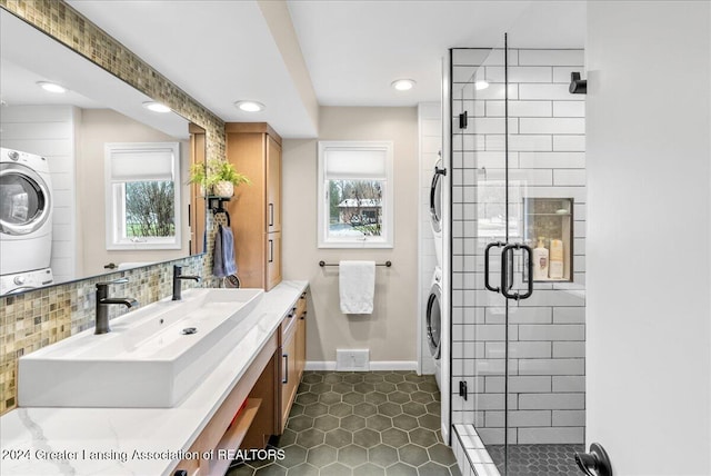 bathroom featuring backsplash, stacked washer and dryer, vanity, and a shower with door