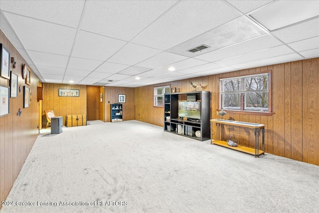 basement featuring carpet floors, a paneled ceiling, and wood walls