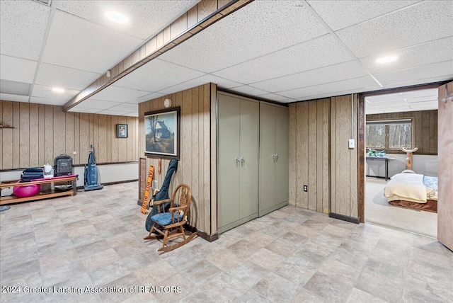 basement with a drop ceiling and wooden walls