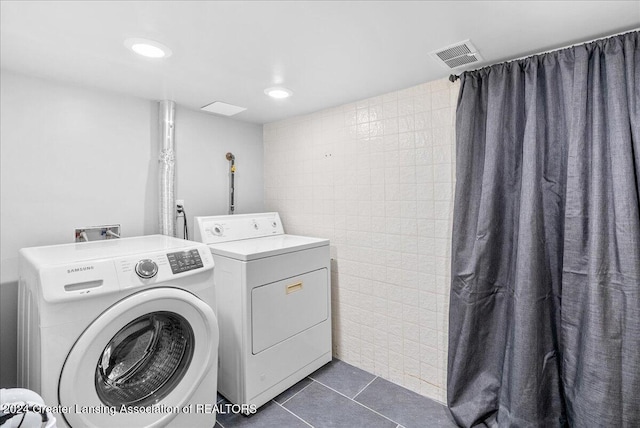 washroom featuring dark tile patterned flooring and washer and dryer