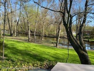 view of property's community featuring a lawn and a water view